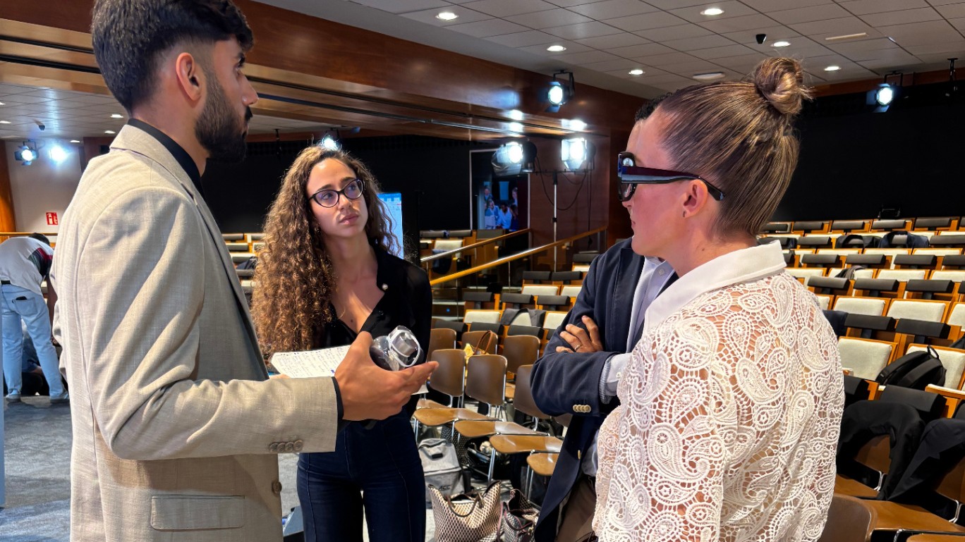 A participant talking with SALUZ faculty during a session break